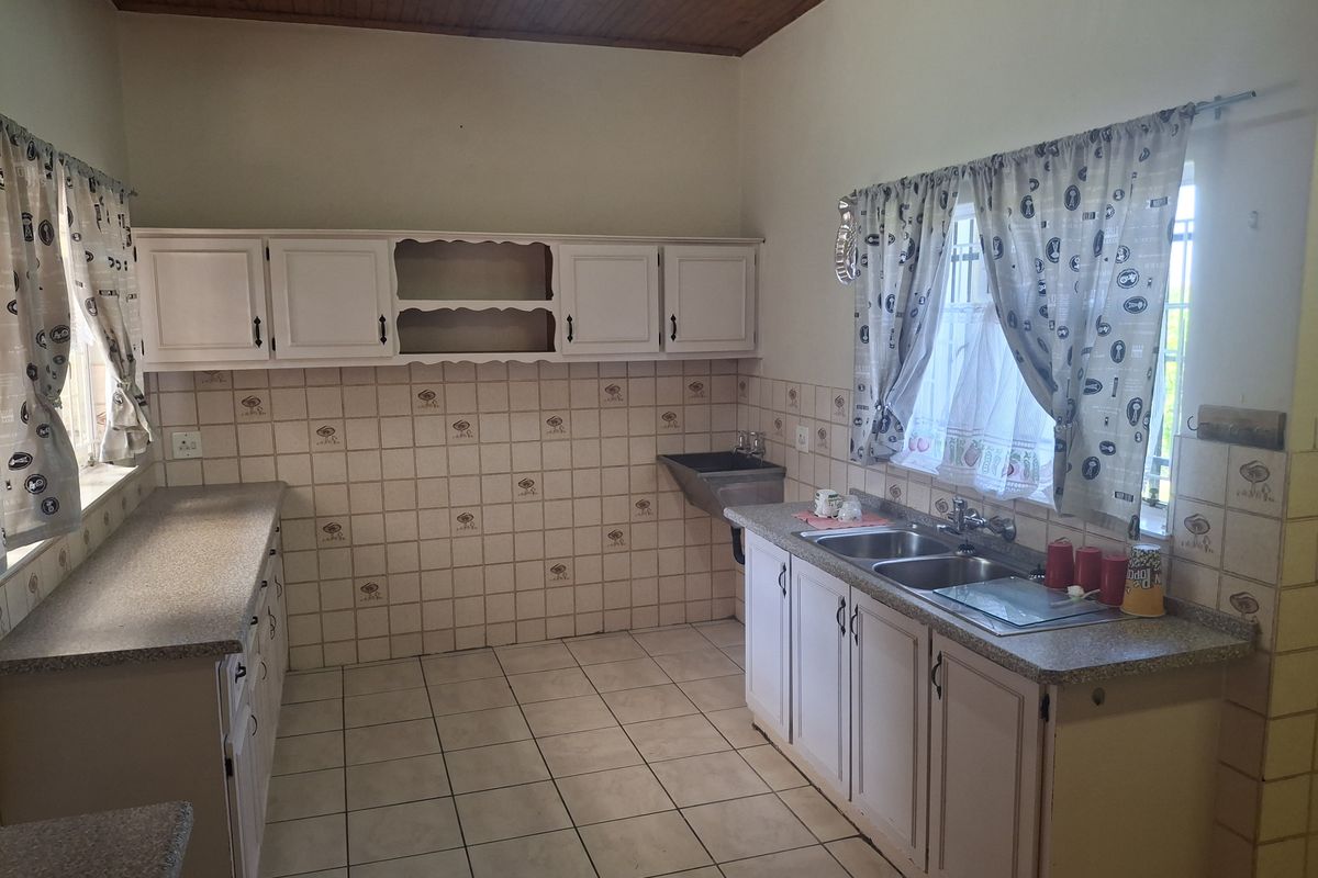 A functional kitchen featuring built-in cabinetry, laminate countertops, a double bowl sink, and ceramic tiling throughout.