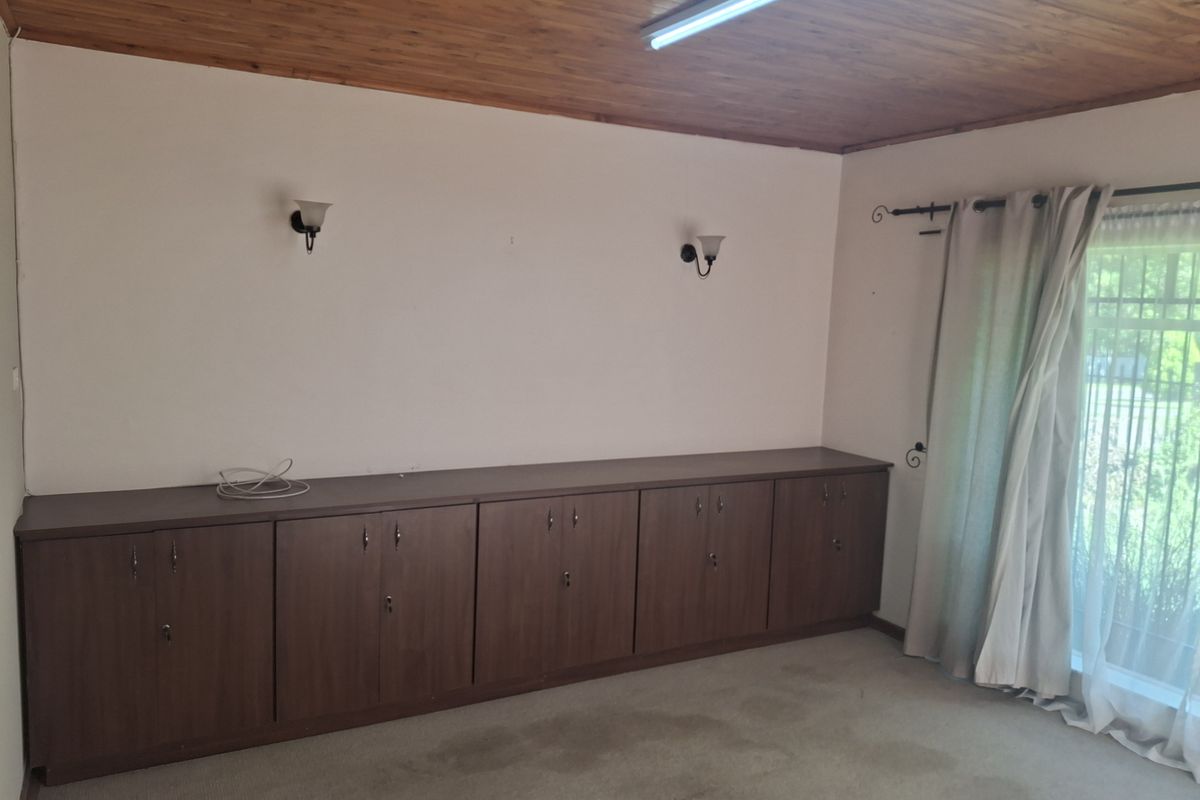 A living area featuring built-in storage cabinetry, a timber-paneled ceiling, and wall-mounted lighting fixtures.