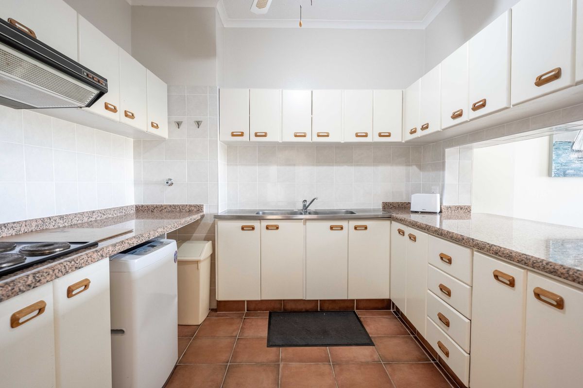 A functional kitchen featuring white cabinetry, granite-look laminate countertops, a stainless steel double sink, and ceramic tile flooring.