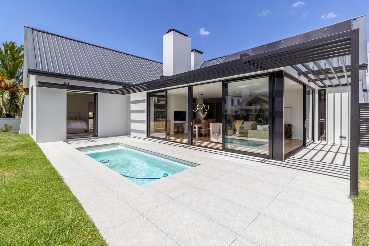 Modern rear exterior featuring a swimming pool, tiled patio, pergola, and large sliding glass doors connecting to the interior living space.