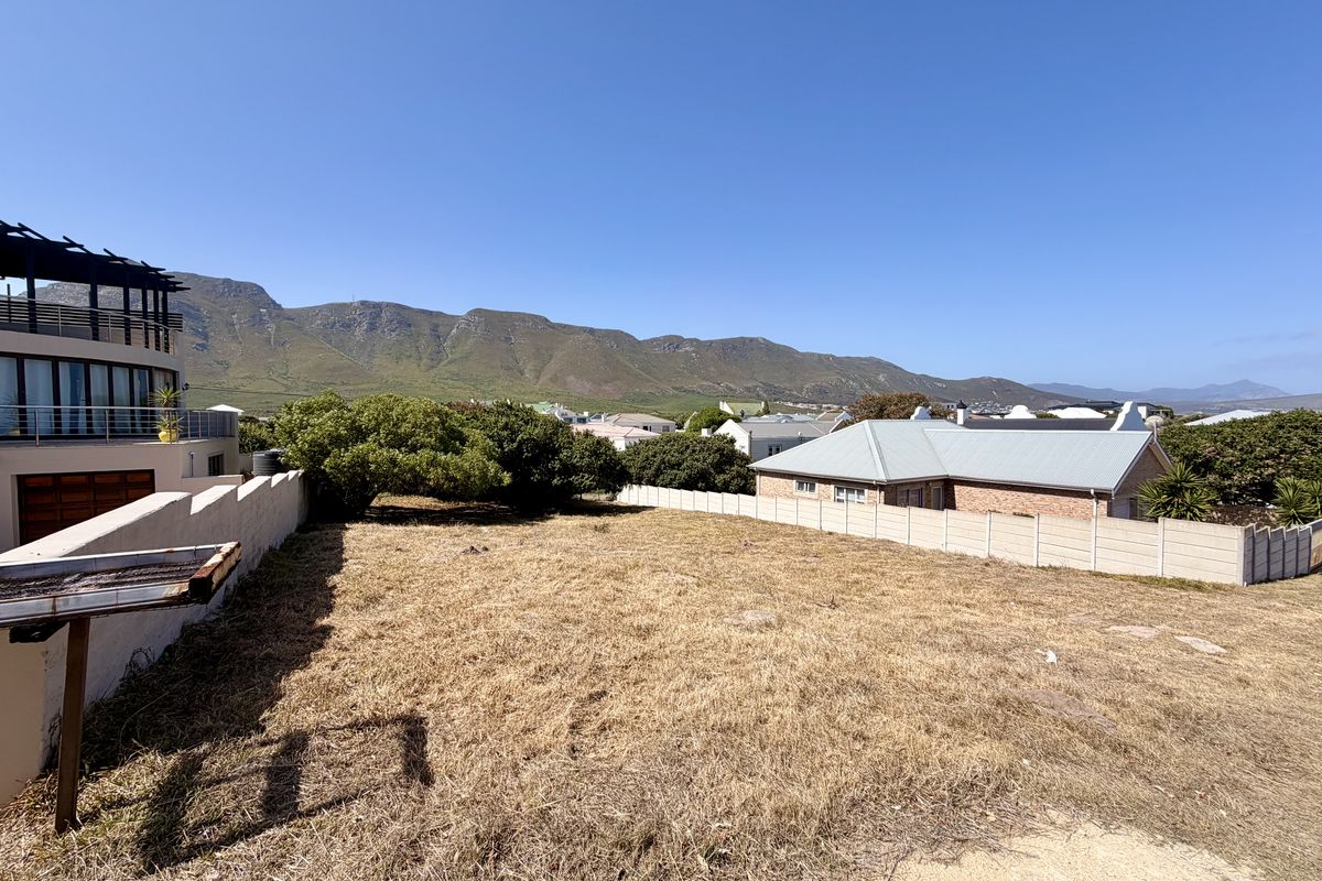 A vacant residential plot featuring boundary walls and scenic mountain views, offering a clear space for potential development.
