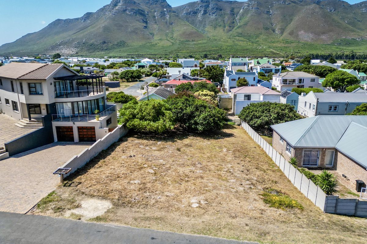 An aerial view of a vacant residential plot situated in a developed neighborhood with mountain views.