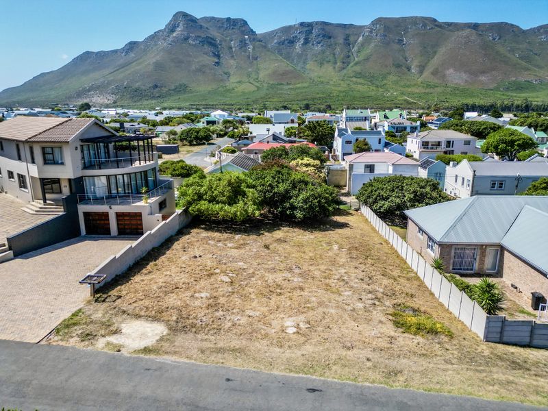 An aerial view of a vacant residential plot situated in a developed neighborhood with mountain views.