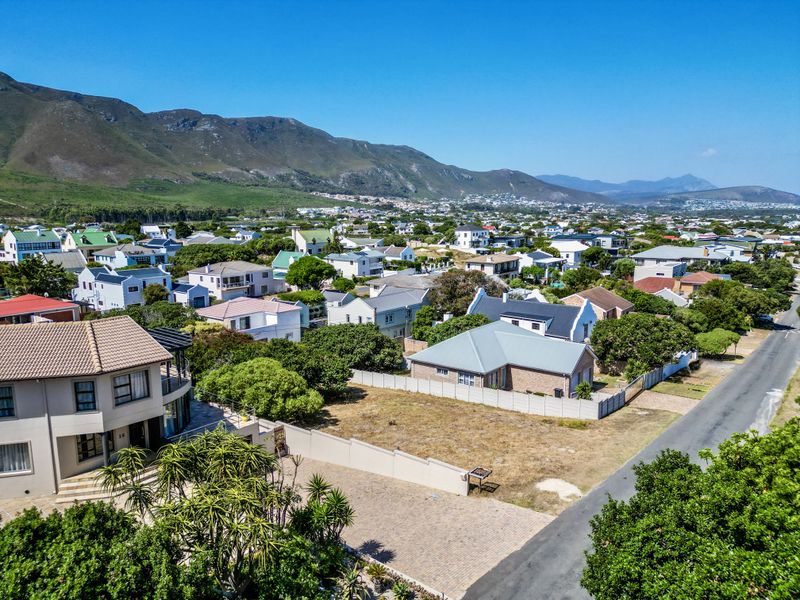 Aerial view of a vacant residential plot situated in a developed neighborhood with mountain views in the background.