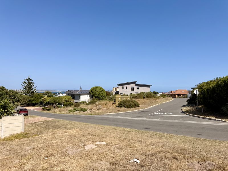 A clear street-level view of the residential neighborhood approach, featuring paved roads and surrounding coastal landscape.