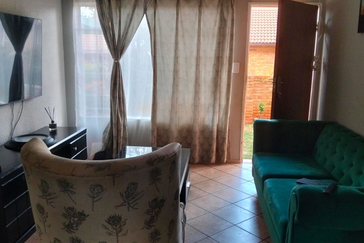 A living room area featuring tiled flooring and direct access to an outdoor space through a doorway.