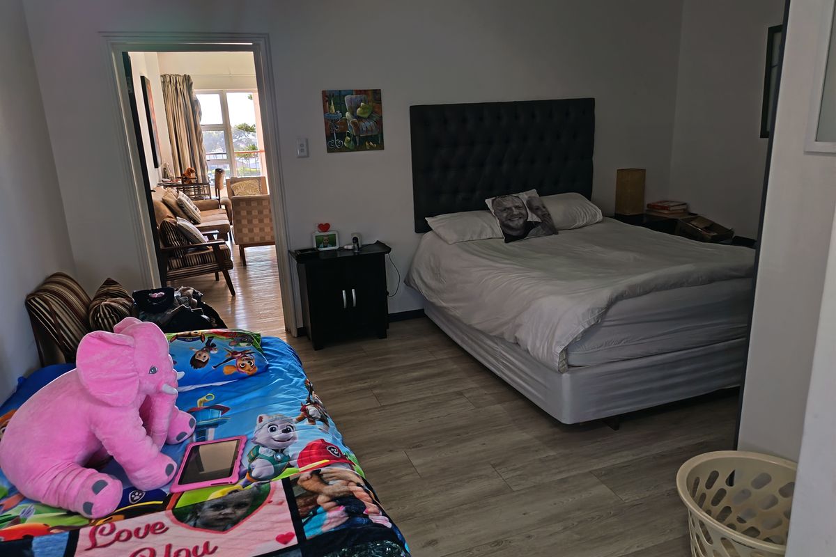Spacious bedroom featuring light-toned laminate flooring and direct access to an adjoining living area.