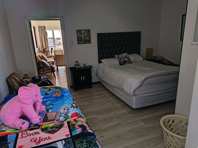 Spacious bedroom featuring light-toned laminate flooring and direct access to an adjoining living area.