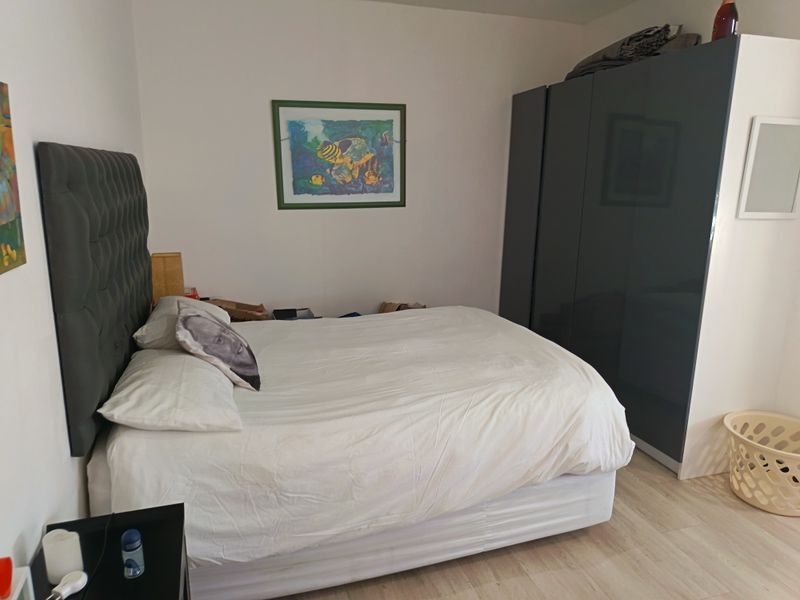 A well-lit bedroom featuring light-toned laminate flooring and a large, dark-toned built-in wardrobe providing ample storage space.