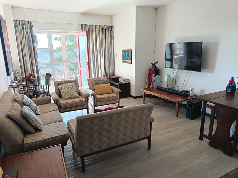A living room featuring laminate flooring and a sliding glass door providing access to an outdoor balcony area.