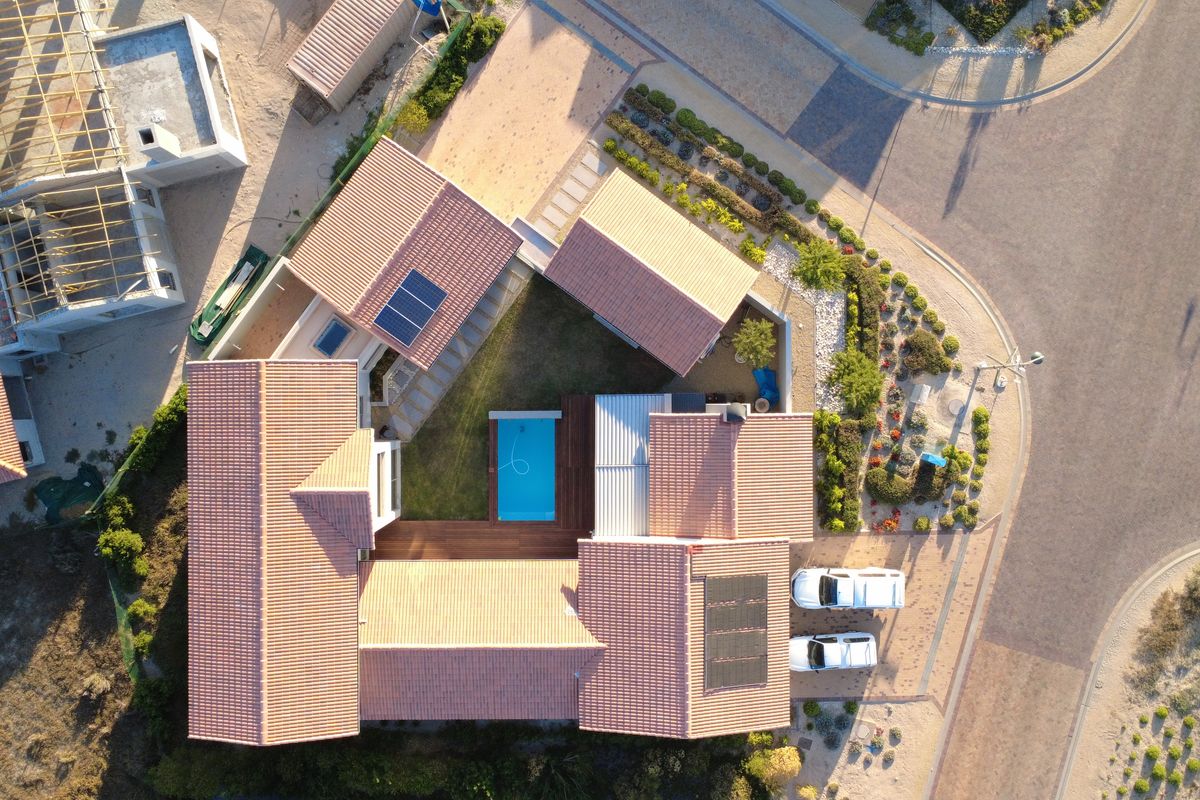 Aerial view of a residential property featuring a tiled roof, swimming pool, wooden decking, and landscaped garden within a suburban estate.
