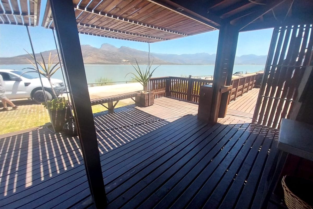 Spacious timber deck patio featuring a pergola and built-in counter, offering expansive views of the lake and surrounding mountains.
