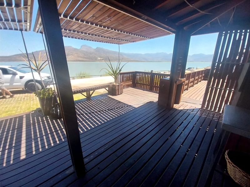 Spacious timber deck patio featuring a pergola and built-in counter, offering expansive views of the lake and surrounding mountains.
