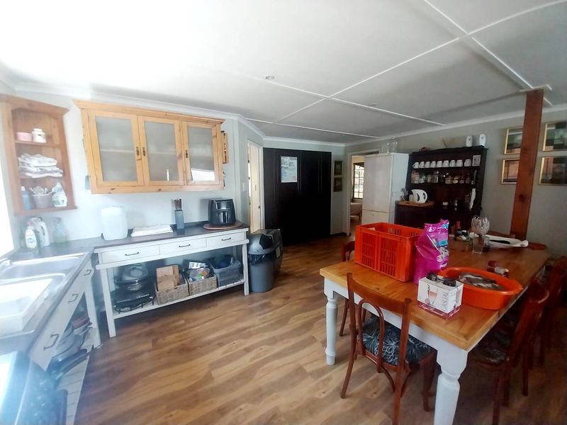 Open-plan kitchen and dining area featuring laminate flooring, built-in cabinetry, and a double sink, offering a functional layout for daily living.
