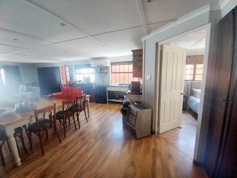 Open-plan living and dining area featuring laminate flooring, recessed lighting, and direct access to an adjacent bedroom.