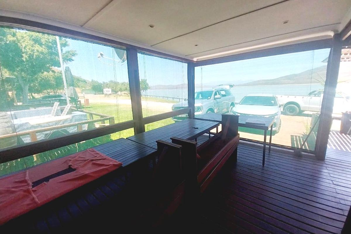 Covered outdoor patio featuring timber decking and support posts, offering views of the surrounding landscape and waterfront area.