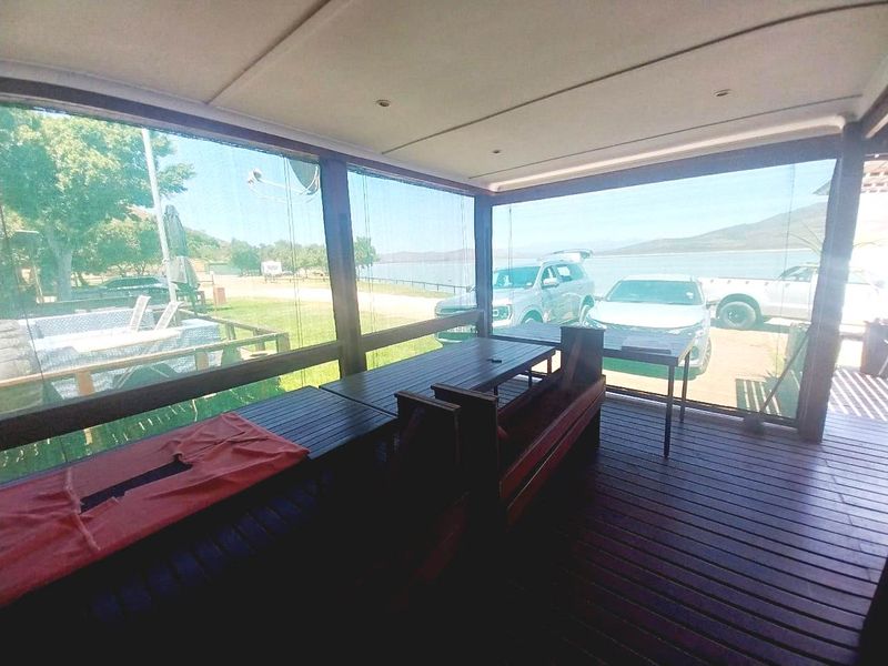 Covered outdoor patio featuring timber decking and support posts, offering views of the surrounding landscape and waterfront area.