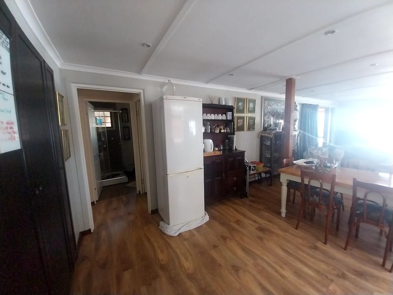 Open plan living and dining area featuring laminate flooring, recessed lighting, and a central timber support post, with access to an adjacent bathroom.