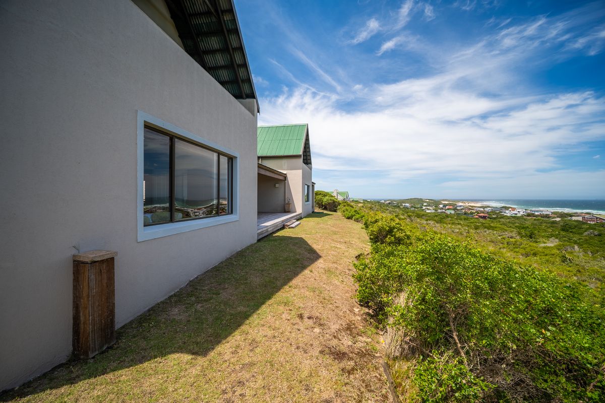 Rear elevation of the property featuring a metal roof, timber decking, and expansive coastal views over the surrounding landscape.