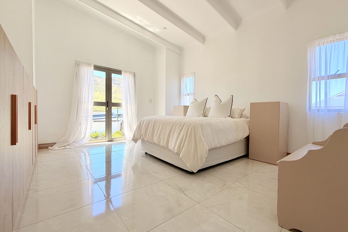 Bright and spacious bedroom featuring vaulted ceilings with exposed beams, polished tiled flooring, built-in cabinetry, and direct access to an outdoor area.