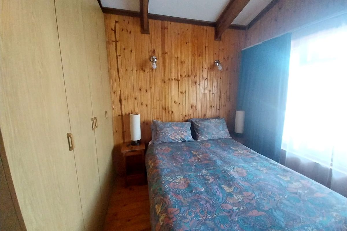 A bedroom featuring timber wall paneling, exposed ceiling beams, and built-in wardrobe cabinetry.