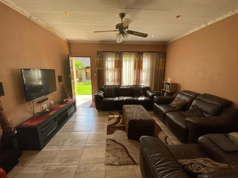 A comfortable living room featuring tiled flooring, recessed lighting, and a ceiling fan, with direct access to the rear garden area.
