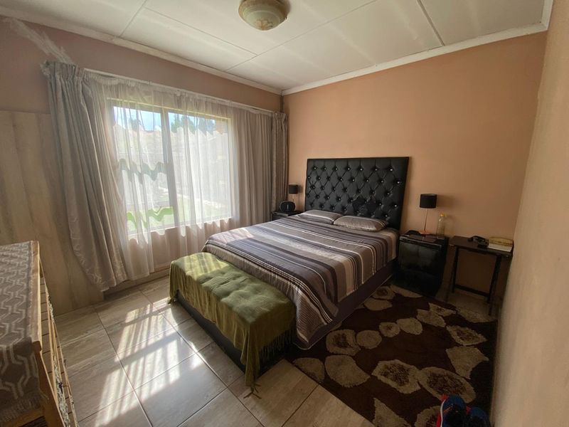 A bedroom featuring tiled flooring and a large window. The room requires cosmetic updates to the ceiling and wall finishes.
