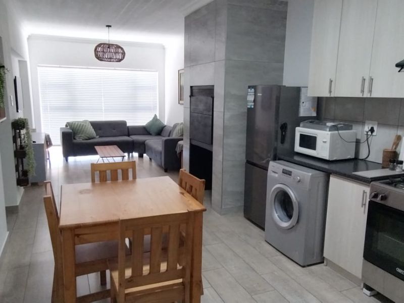 Open-plan living area featuring a modern kitchen with built-in cabinetry, gas stove, and a central fireplace, flowing into a comfortable lounge space.