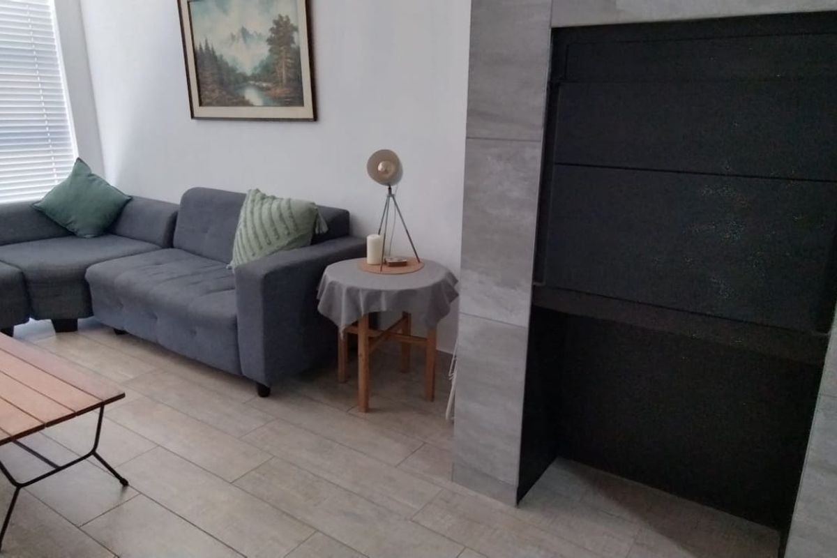 A comfortable living room featuring modern tiled flooring and a prominent built-in fireplace with stone-look tiling.
