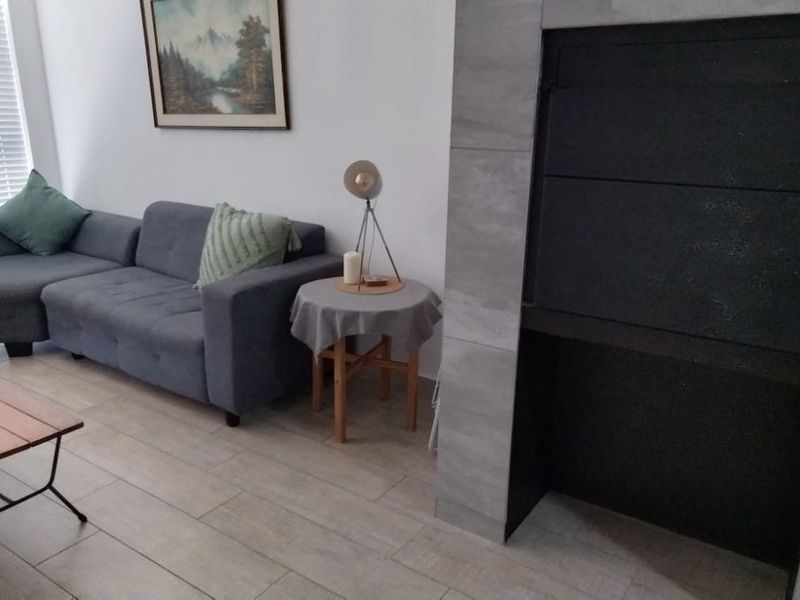 A comfortable living room featuring modern tiled flooring and a prominent built-in fireplace with stone-look tiling.