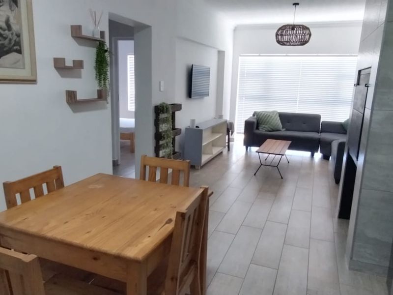 Open-plan living and dining area featuring tiled flooring, a built-in fireplace, and natural light through large windows with venetian blinds.