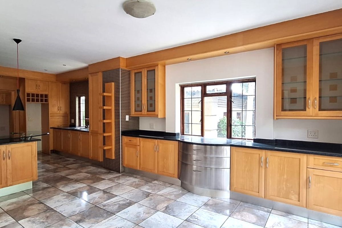 Spacious kitchen featuring extensive wooden cabinetry, granite countertops, built-in double oven, and tiled flooring with a functional layout.