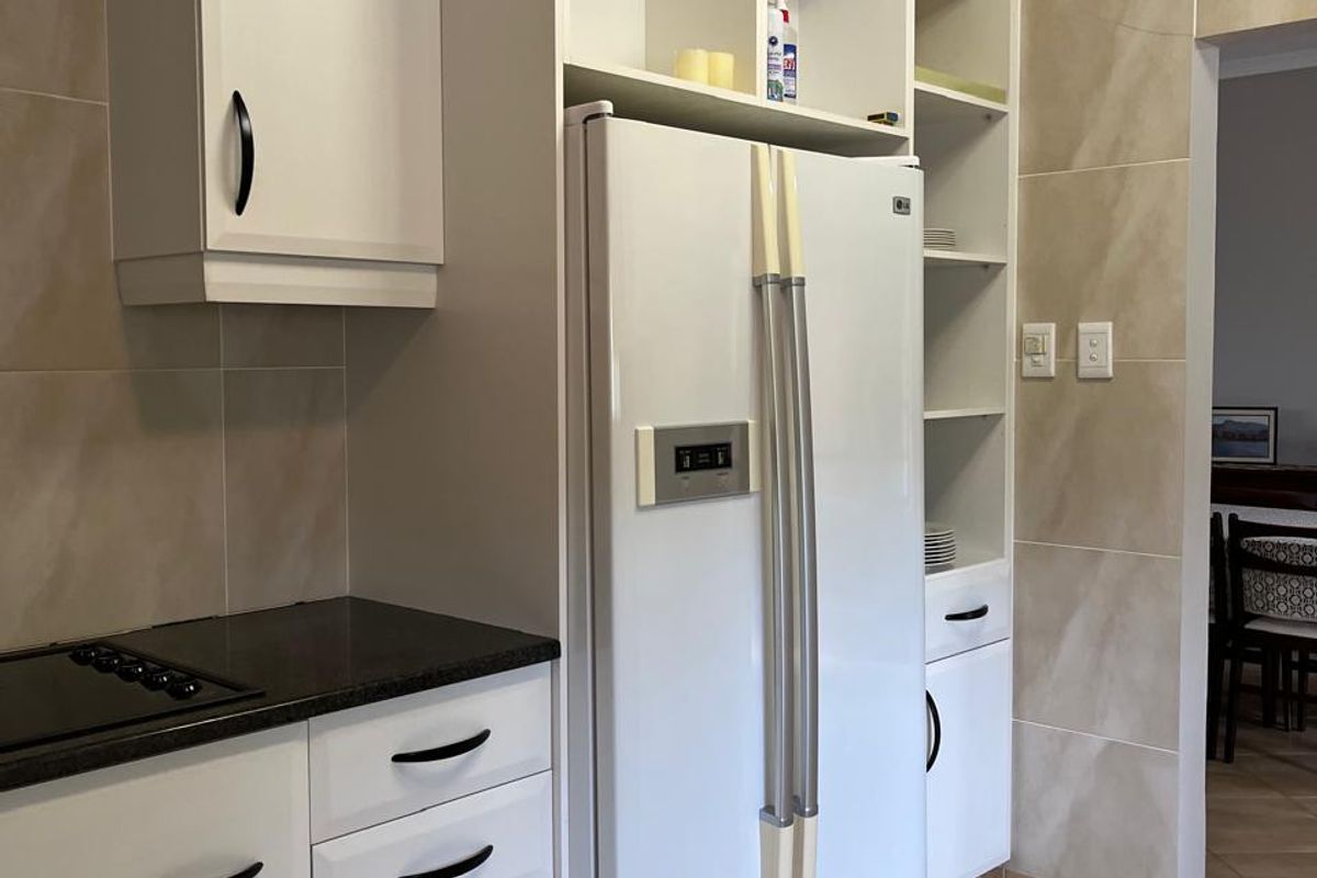 A well-maintained kitchen featuring white cabinetry, dark granite countertops, and neutral ceramic tiling throughout.