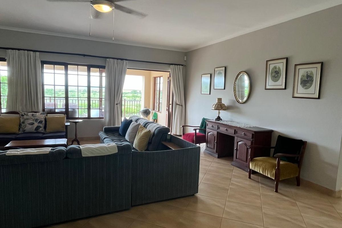 Spacious living room featuring tiled flooring, a ceiling fan, and large sliding glass doors that provide access to an outdoor patio area.