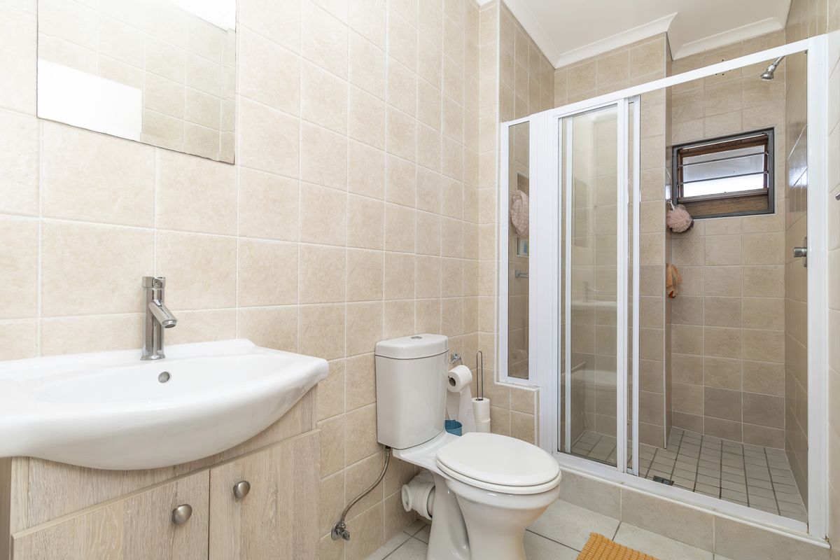 A functional bathroom featuring a vanity with basin, a toilet, and a separate shower enclosure with tiled finishes throughout.