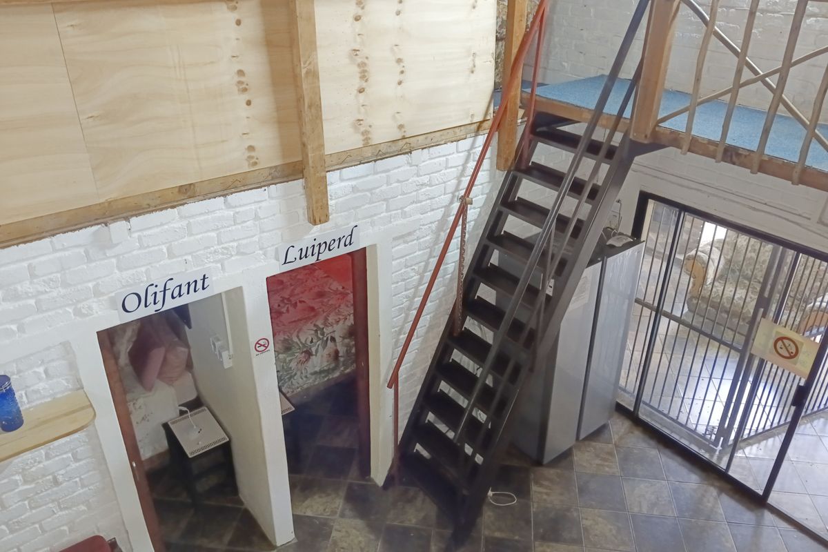 Interior view of a multi-level living space featuring a timber staircase, mezzanine level, and painted brick walls with access to separate rooms.