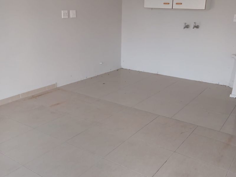 A vacant laundry area featuring tiled flooring, wall-mounted storage cabinetry, and dedicated plumbing connections for laundry appliances.