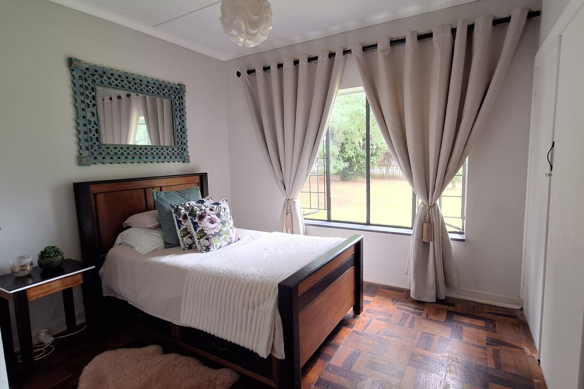 A well-maintained bedroom featuring classic parquet wood flooring, large window with natural light, and built-in closet space.