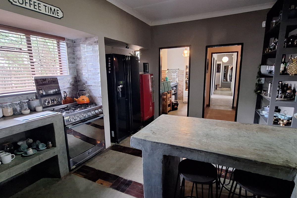 A rustic-style kitchen featuring concrete countertops, a built-in gas stove, and an integrated breakfast bar, with direct access to the hallway.