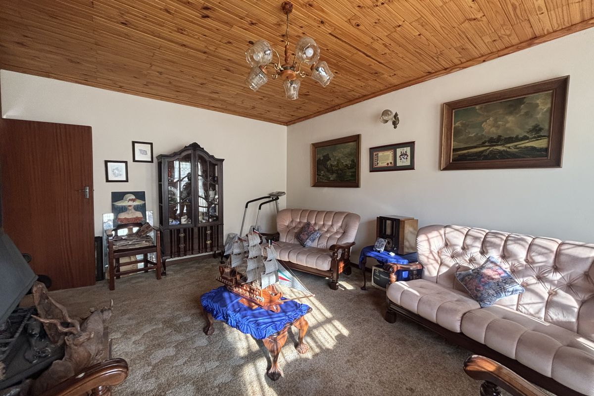 A traditional living room featuring a warm timber tongue and groove ceiling, carpeted flooring, and a built-in fireplace.