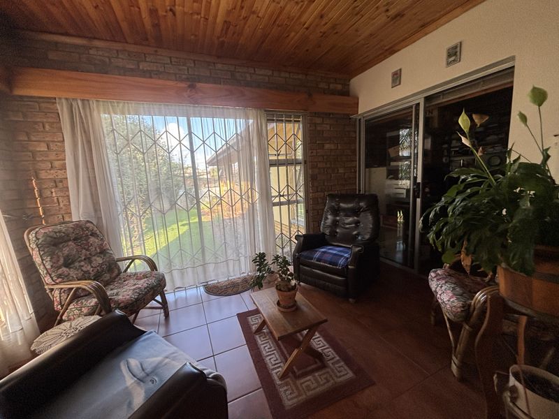 A cozy living area featuring exposed brick walls, a warm timber ceiling, and large sliding doors that provide access to the garden.