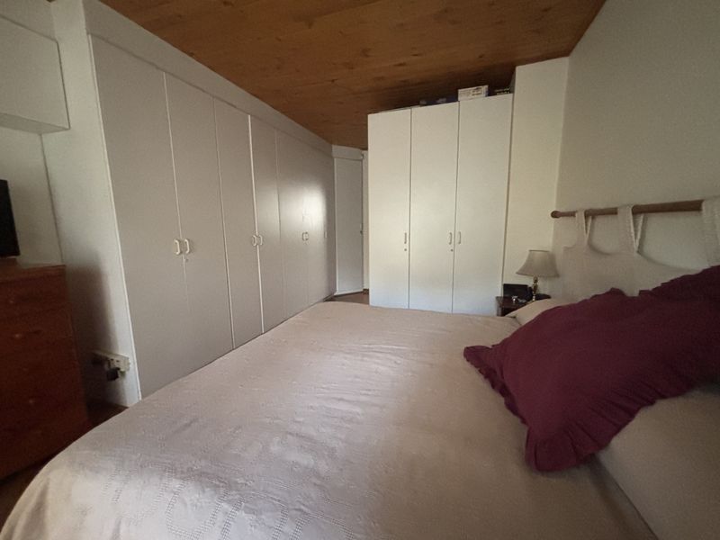 A bedroom featuring extensive built-in white cabinetry and a natural timber ceiling, providing ample storage space.