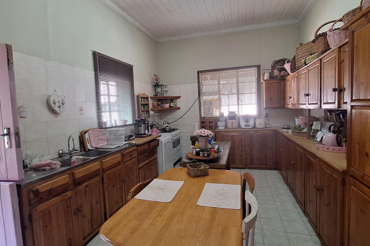 A spacious kitchen featuring extensive wooden cabinetry, tiled countertops, and a functional layout with integrated stove and sink area.