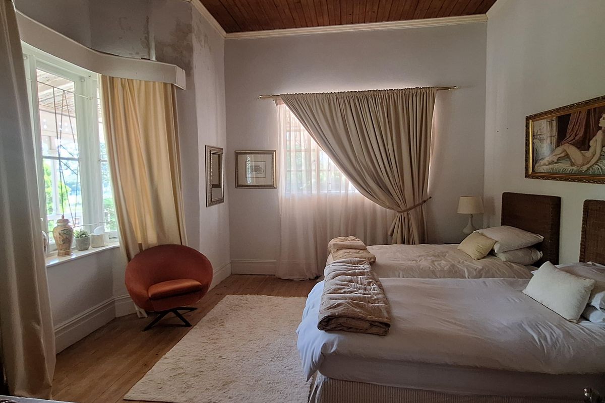 Spacious bedroom featuring original timber ceiling, polished wooden flooring, and large bay windows allowing for ample natural light.