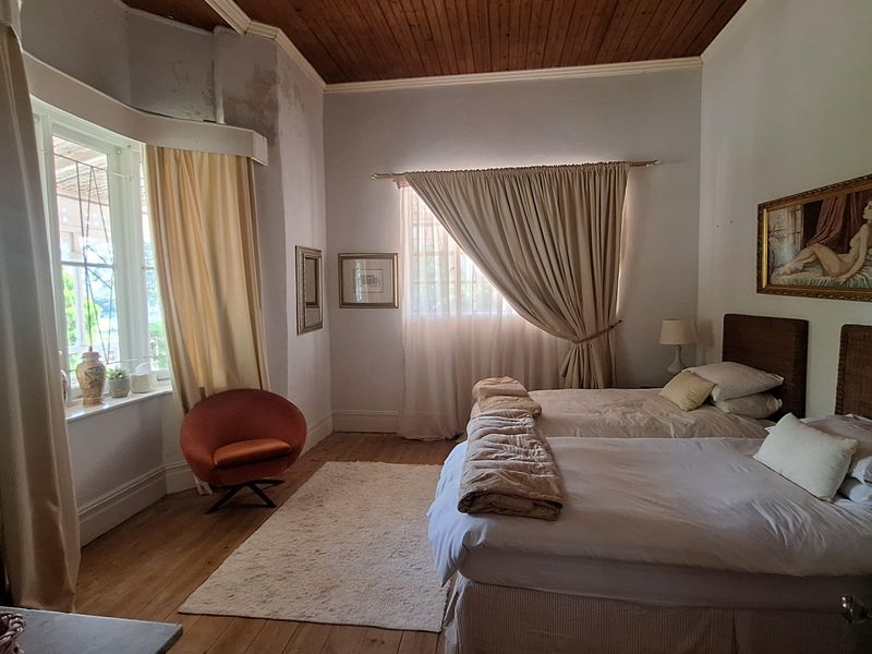 Spacious bedroom featuring original timber ceiling, polished wooden flooring, and large bay windows allowing for ample natural light.
