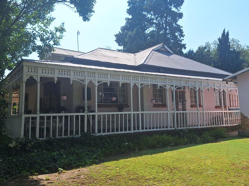 A charming period-style house featuring a classic wrap-around veranda with intricate white timber fretwork and a corrugated metal roof.