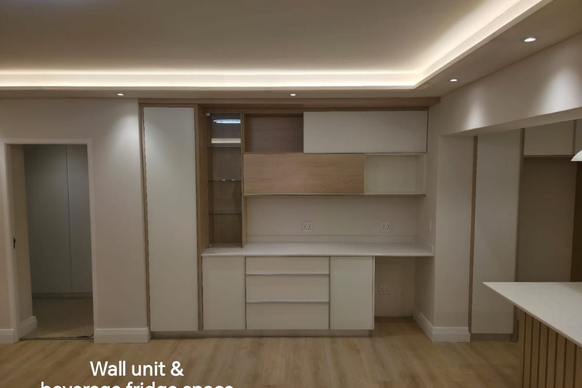 Modern living area featuring custom built-in cabinetry with integrated shelving, stone countertop, and elegant recessed cove lighting.