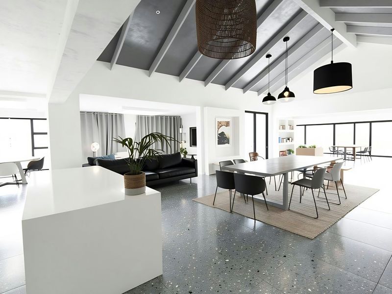 Spacious open-plan living and dining area featuring a vaulted ceiling with exposed beams, modern terrazzo flooring, and abundant natural light.