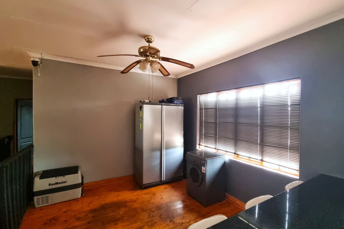 A functional utility or kitchen area featuring timber flooring, a ceiling fan, and a window with fitted blinds.