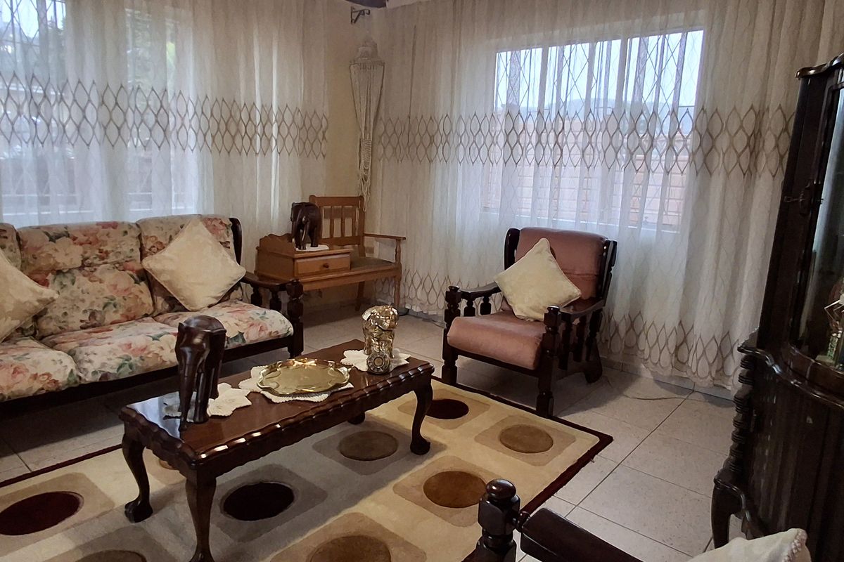 A living room featuring tiled flooring and large windows fitted with security bars, offering a functional and well-lit space.